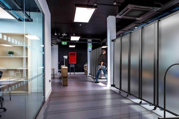 Translucent polycarbonate partition panels line a modern office hallway.