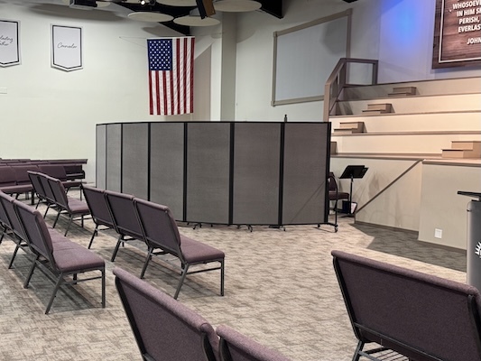 Gray portable room dividers screen off an area beside tiered seating in a church sanctuary.