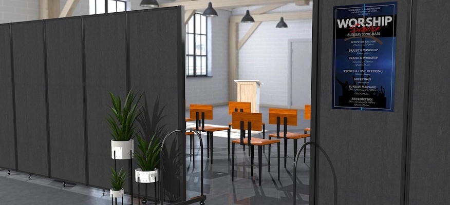 Gray room dividers create an entrance to a worship area, with a service program displayed on one panel.