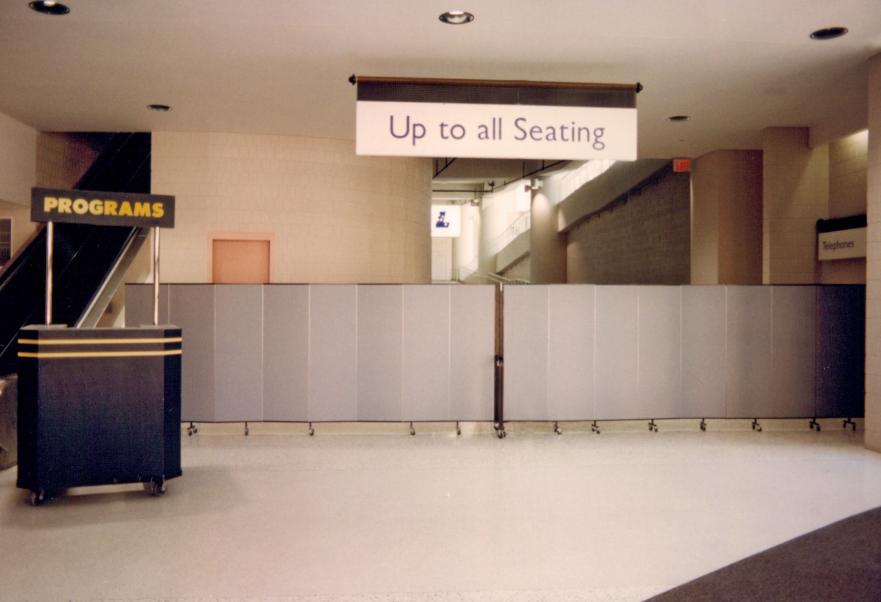 A pair of room dividers are locked together to create a barrier to a hallway in a stadium