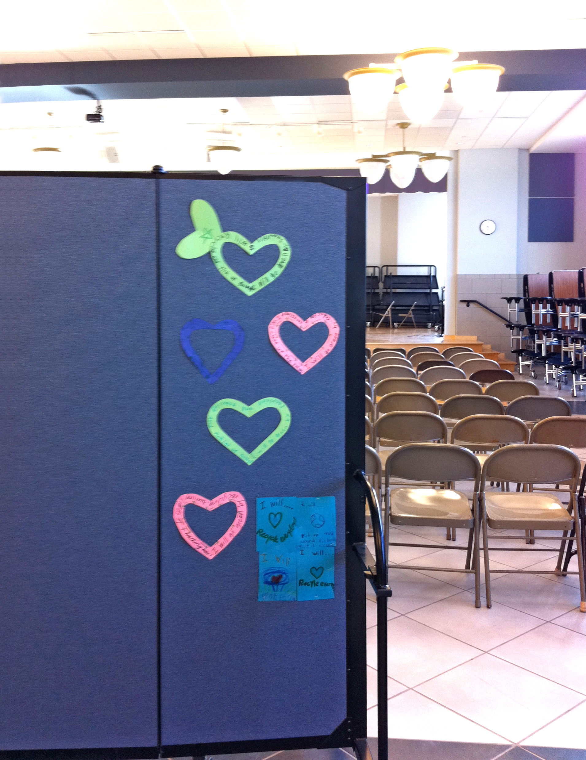 5 decorative hearts tacked to a room divider in the rear of church hall