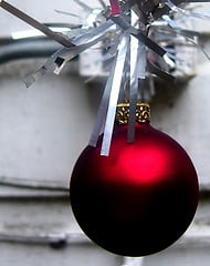 A red ornament hanging amongst a grey background