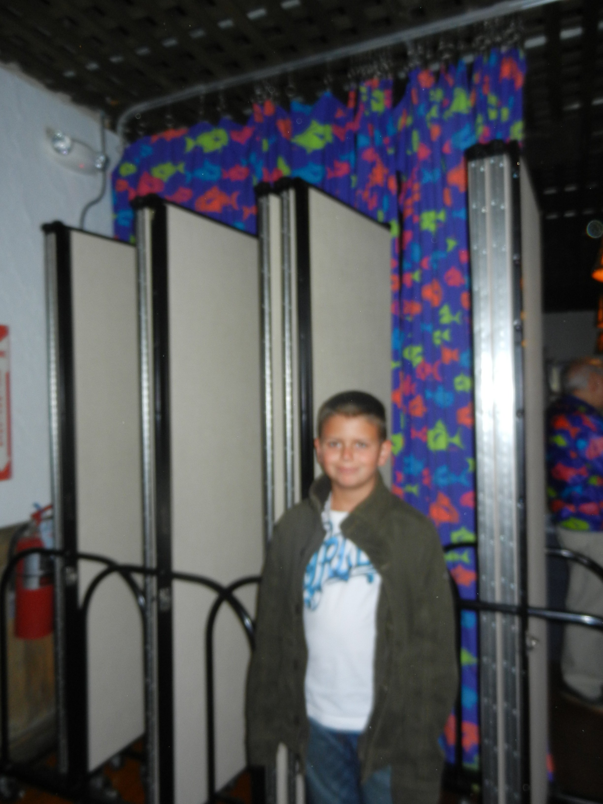 A teen boy stands in front of 4 closed room dividers