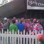 A group of men at a PGA tournament wear hats and jumpsuits resembling the British Flag