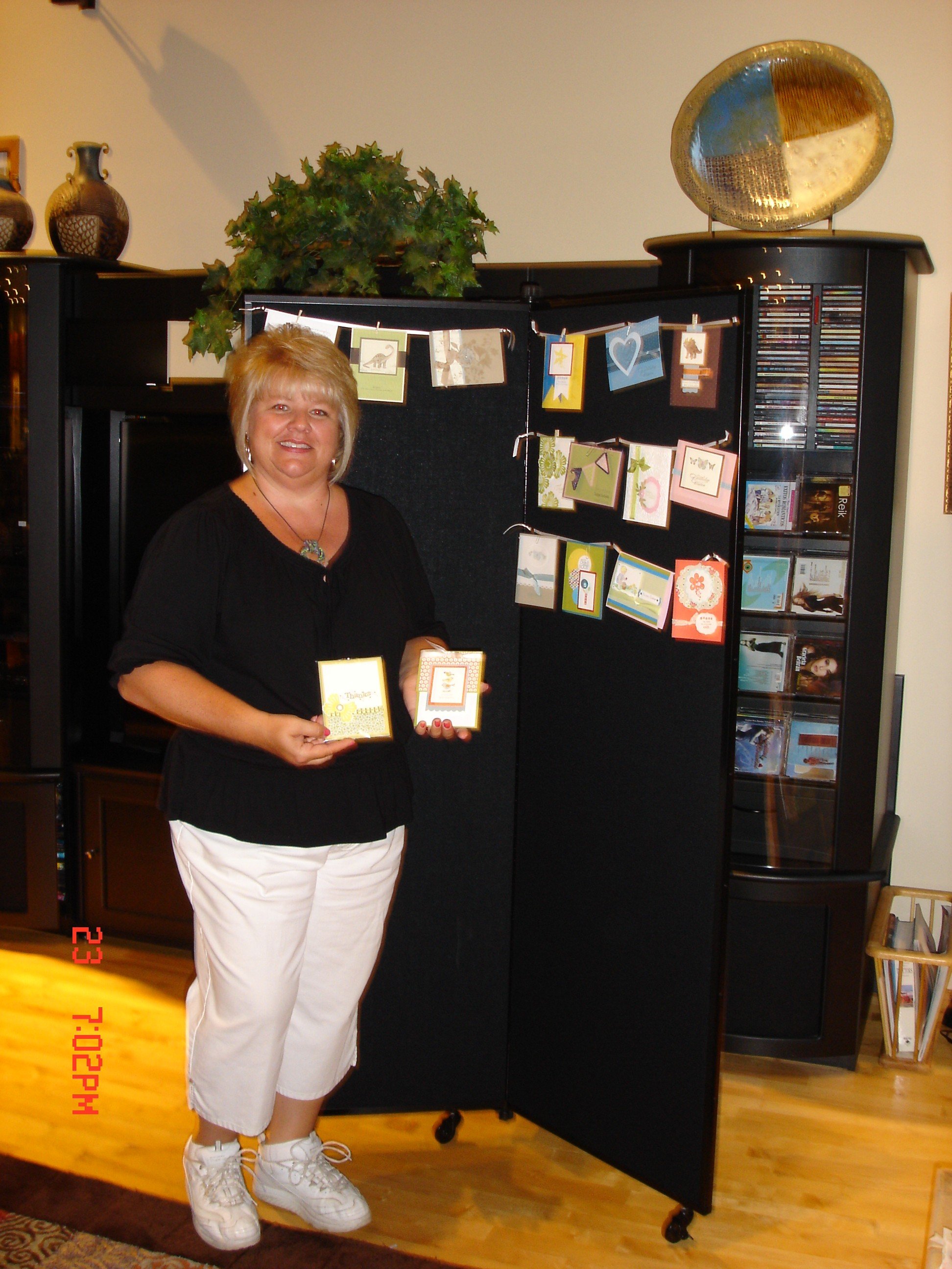 A female hangs homemade Stampin Up cards on a black Screenflex Display unit