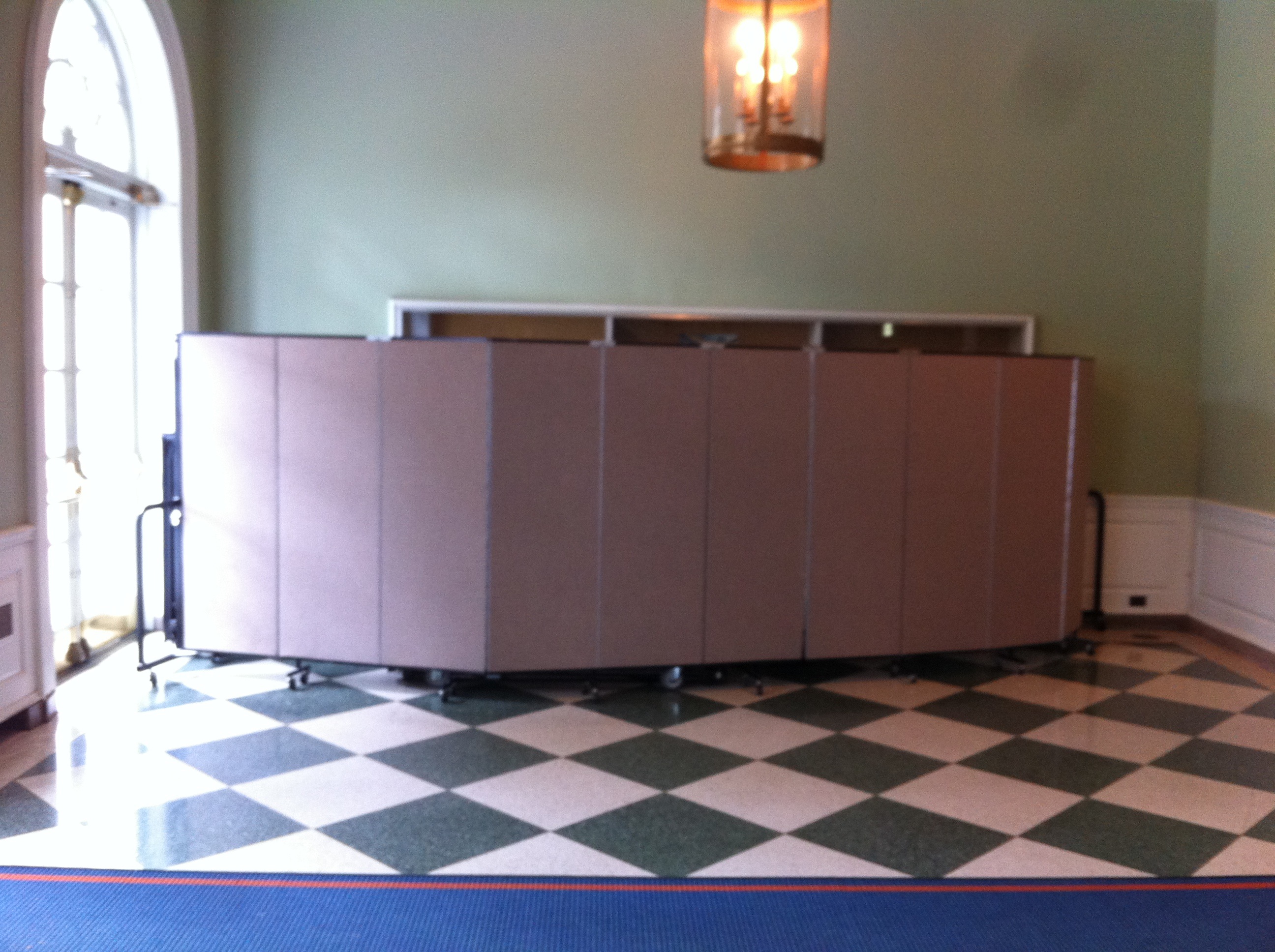 Room divider hides stacked chairs in a banquet hall entryway in a private storage space