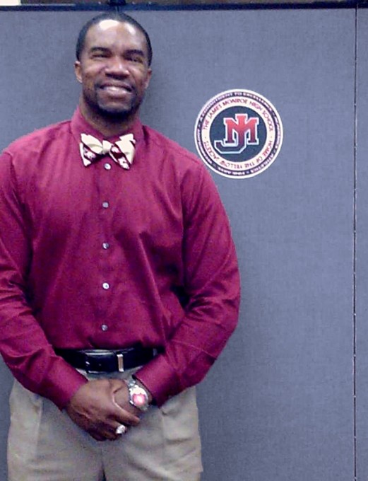 Man stands next to a Screenflex Room Divider with a James Monroe High School Logo on the divider.