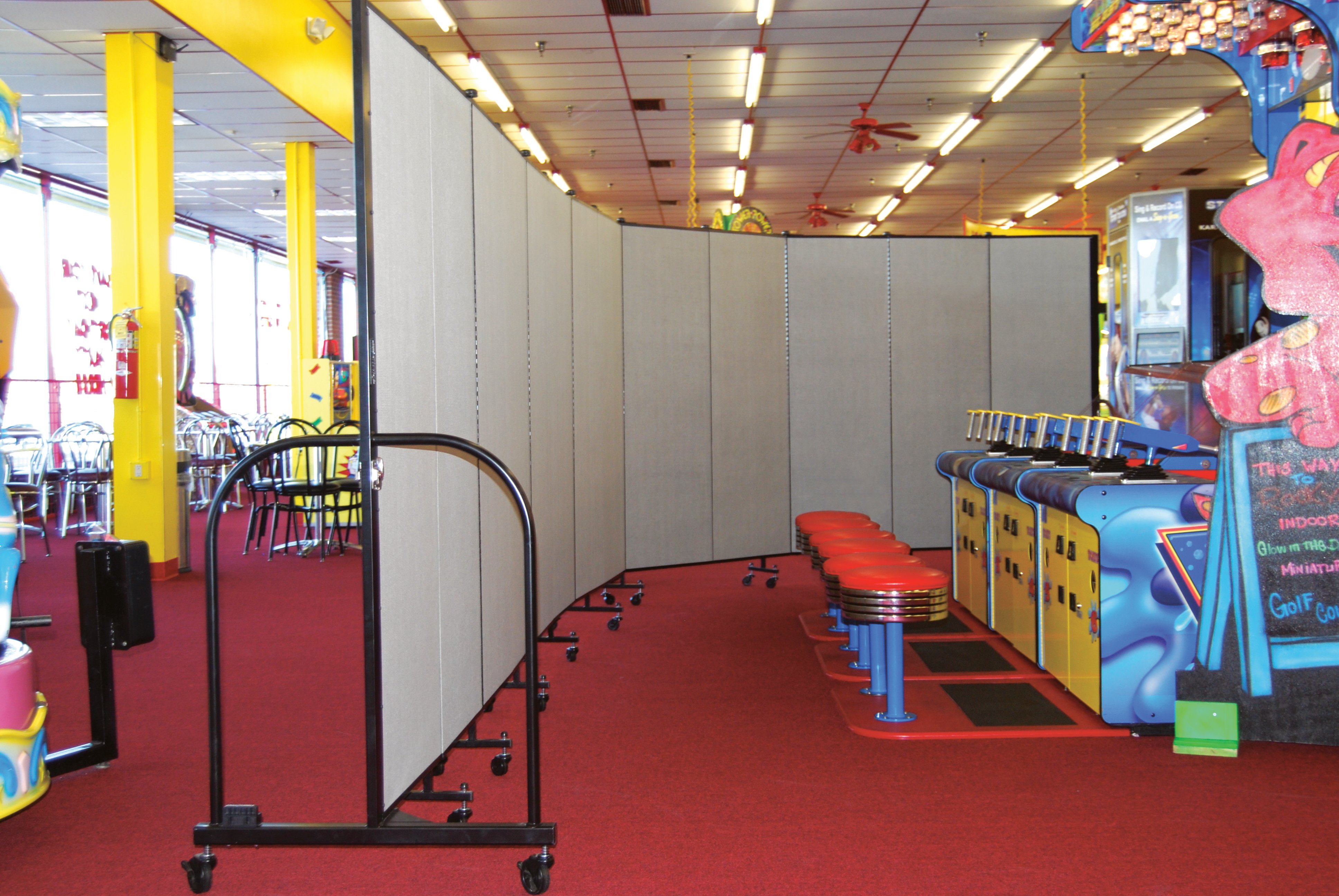 Screenflex Room Divider separates cafeteria from game room at an indoor game center.