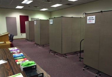 Four room dividers each arranged in an L-shape create four private medical screening rooms 