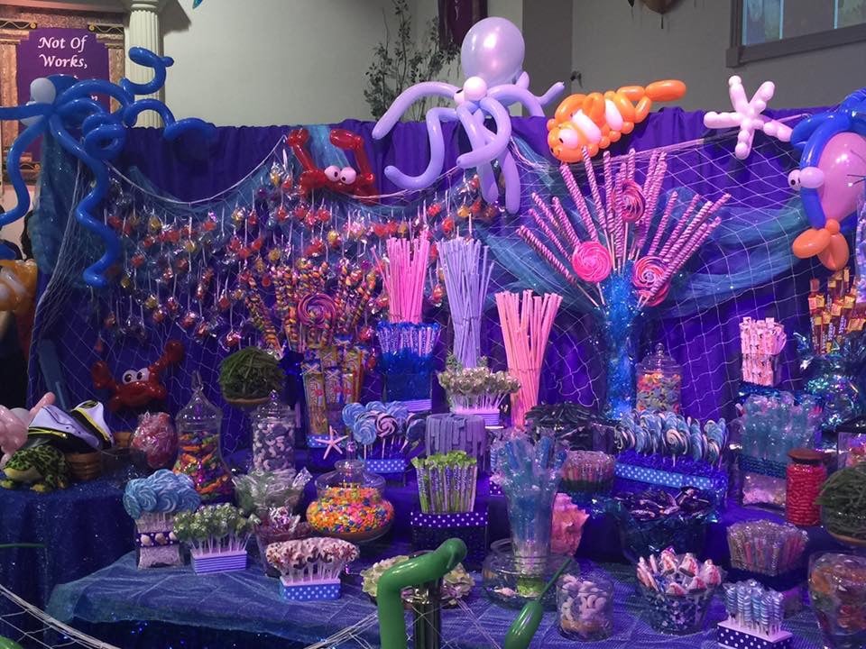 Balloon sea creatures, fish net and candy hide a hidden rolling wall in the back of a large candy table