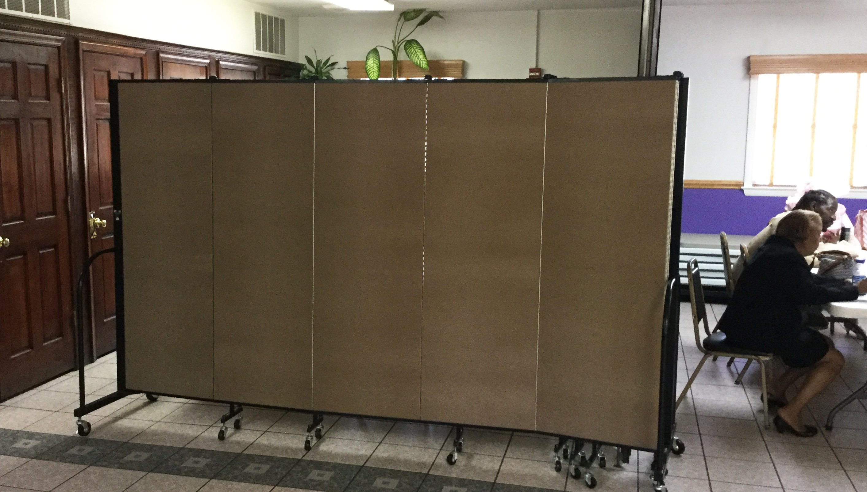 A folding room divider creates a storage area in a fellowship hall