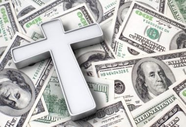 A cross laying on top of 100 dollar bills