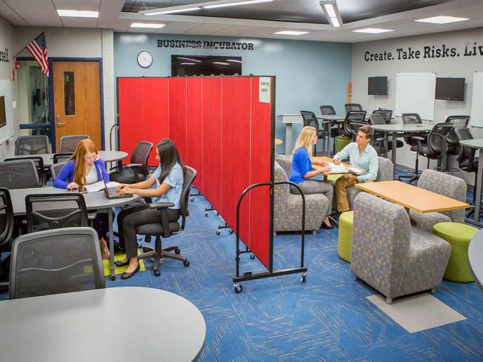 A set of students on each side of a portable room divider splitting a classroom in two