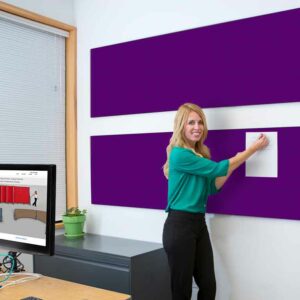 A woman tacks a piece of paper to a tackable wall panel