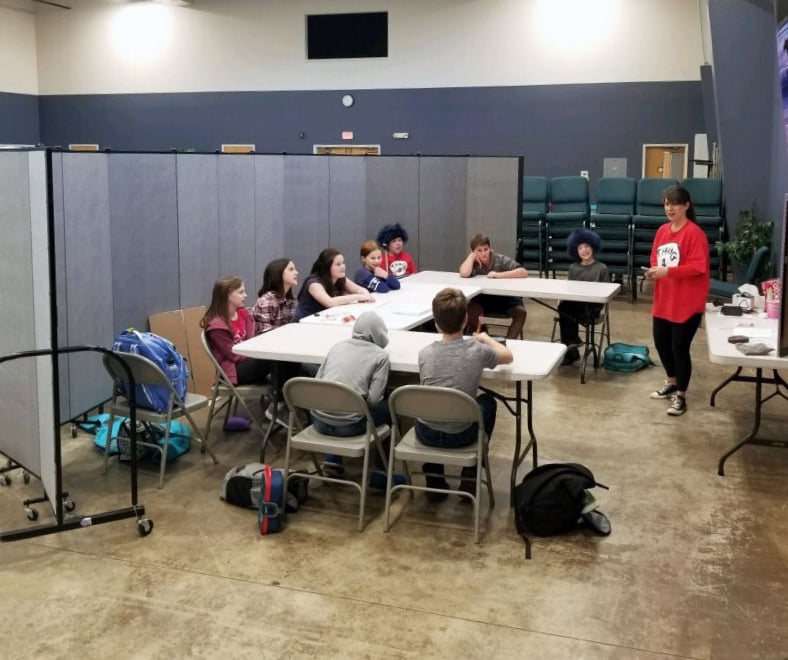 A teacher talks to a group of students sitting at a table