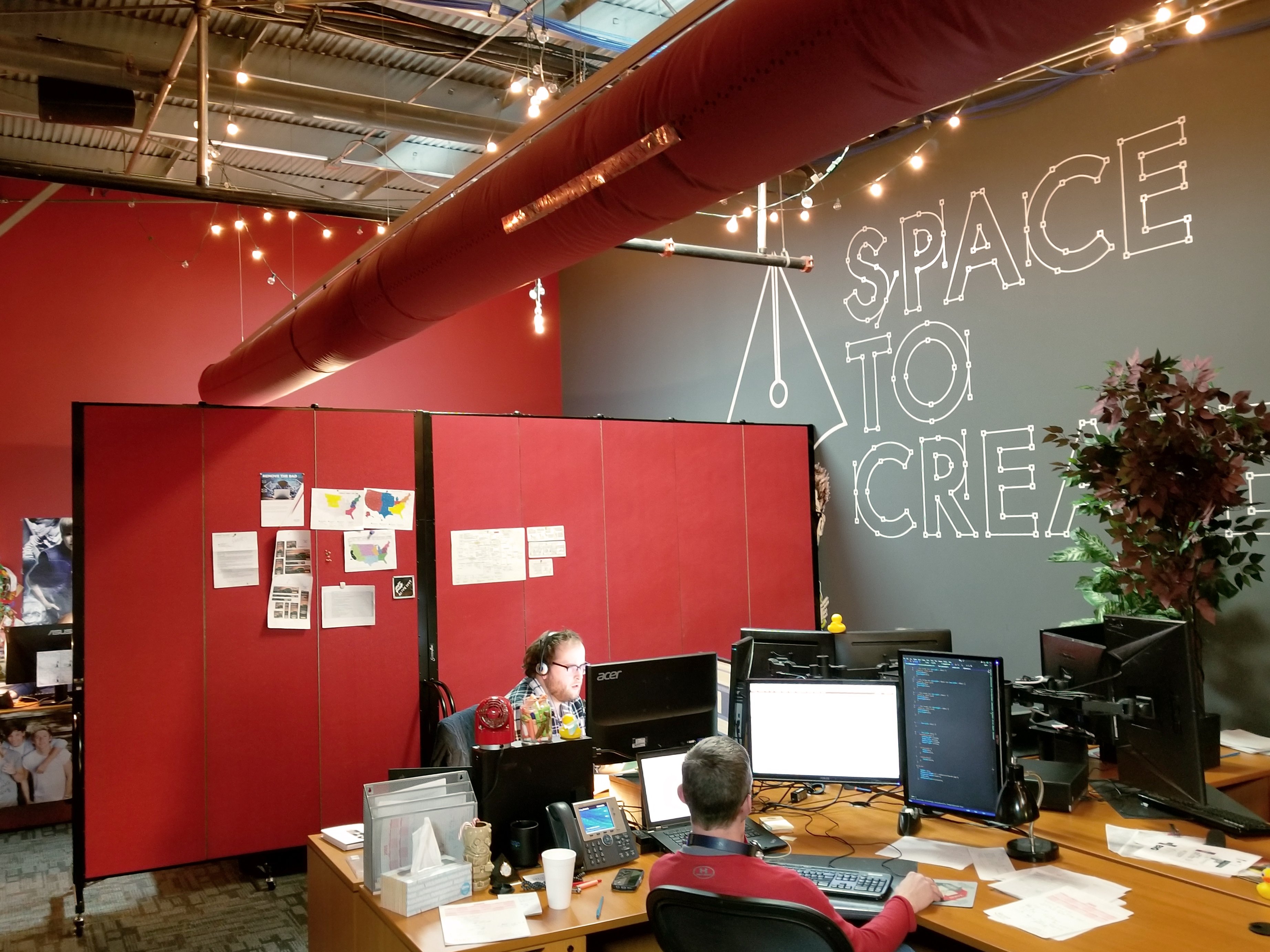 A set of red tackable room dividers separate an office into two rooms