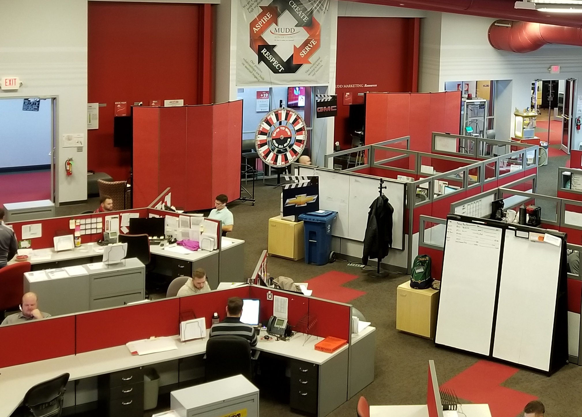 A set of red dividers provide private meeting space in a crowded open office space