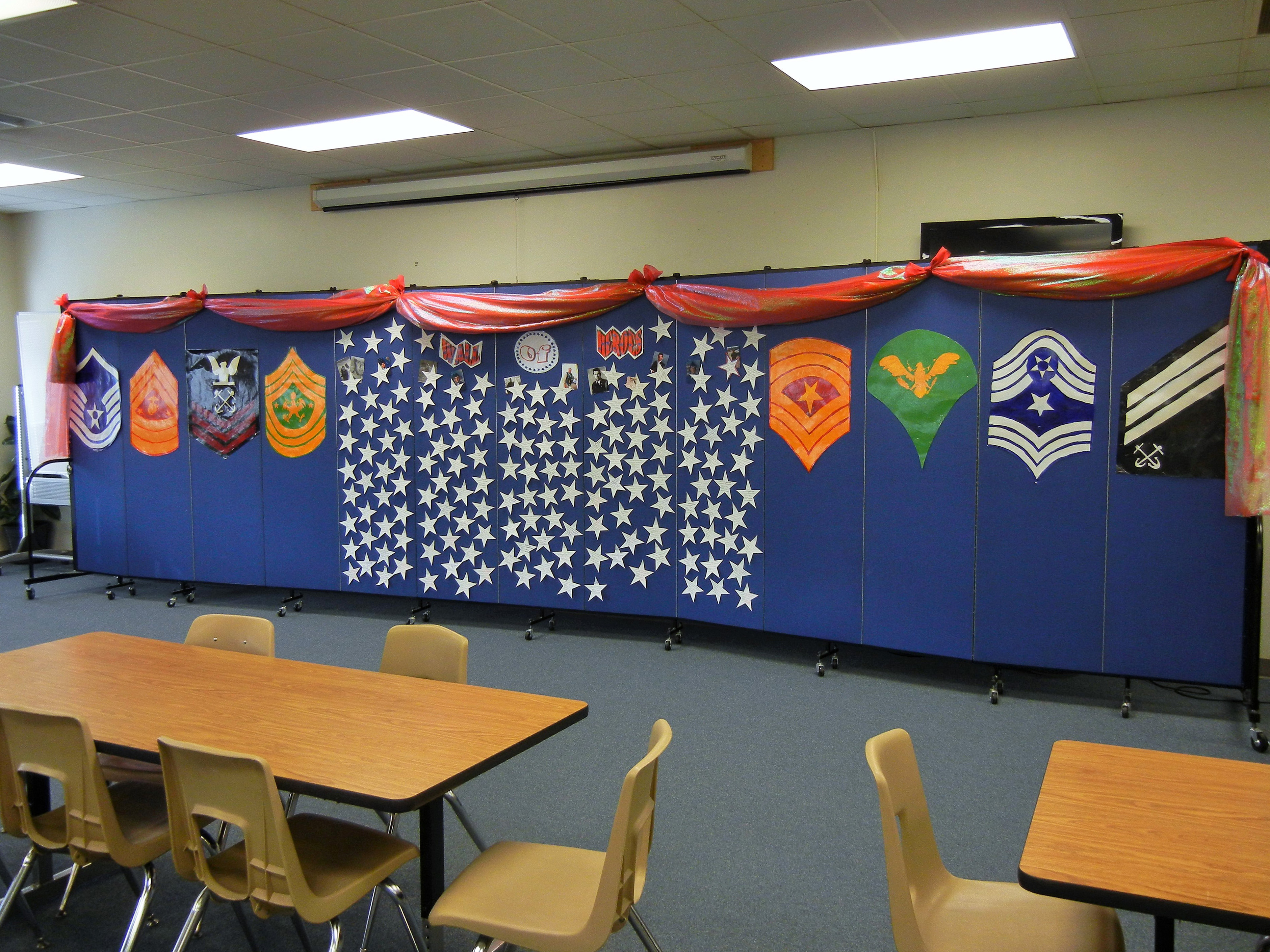 Veteran emblems and plaques are tacked to a blue movable wall