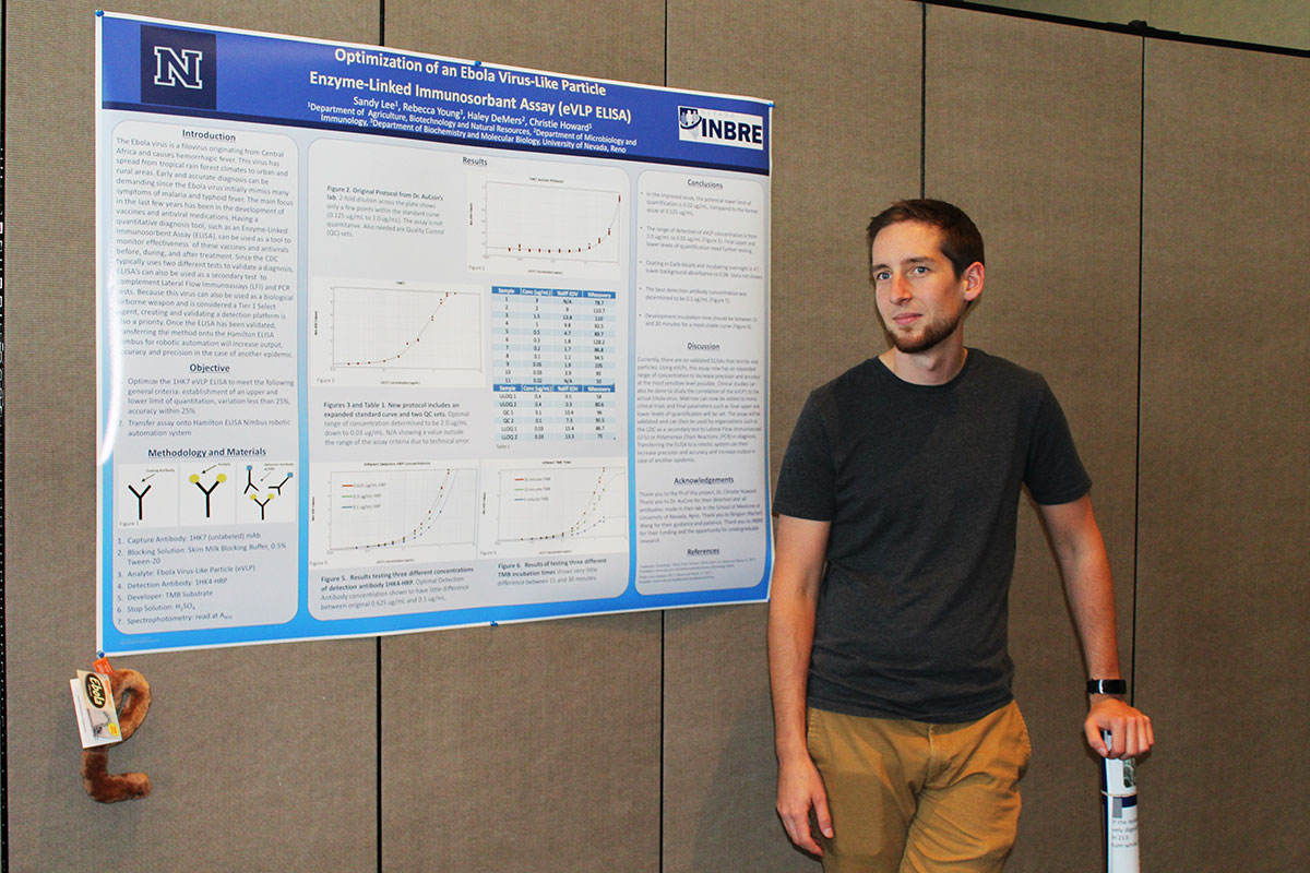 A man stands beside his college research poster on display