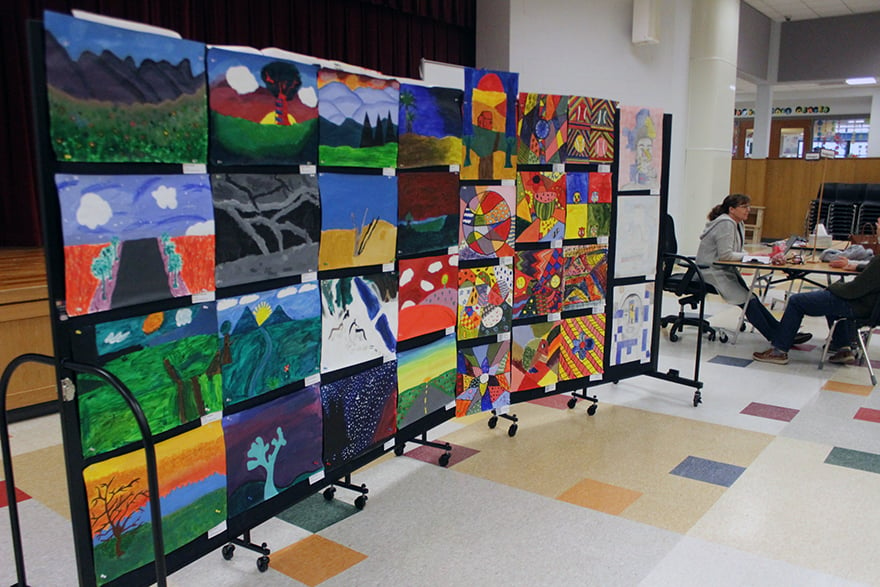 Teachers look on as a student art display is next to them.