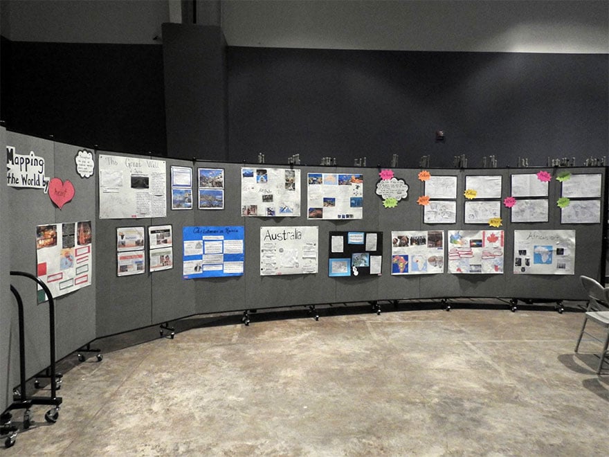 Student presentation posters displayed on a portable wall in a curved position