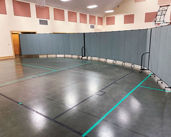 Two blue room dividers side-by-side in an arch inside a gym