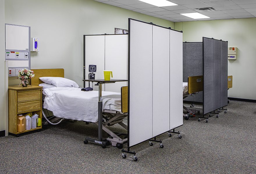 A set of medical privacy screens separate two hospital beds