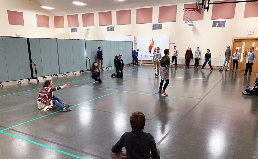 Students play a game in a gym on one side of portable wall