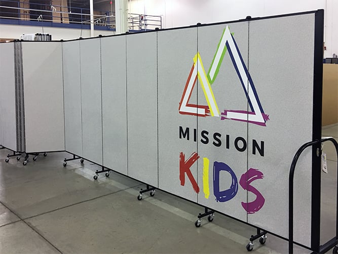 Portable partition with a custom logo greets students in at Mission Kids church program