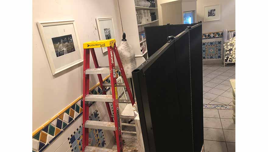 Ceiling repair equipment hidden behind a black divider wall in a store