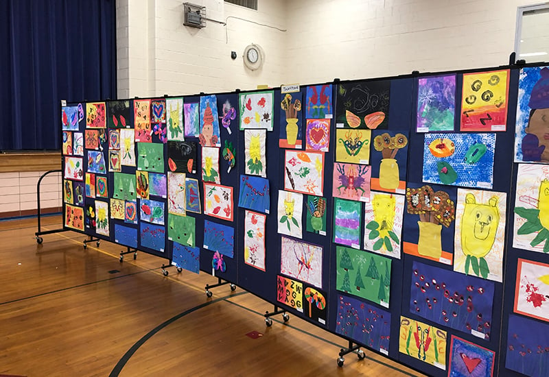 Artwork displayed on a black room divider in a middle school gym