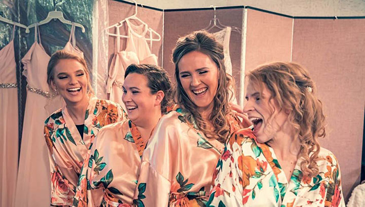 bride and her bridesmaids posing in front of a backdrop