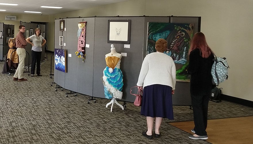 art displayed on freestanding walls and people standing around them