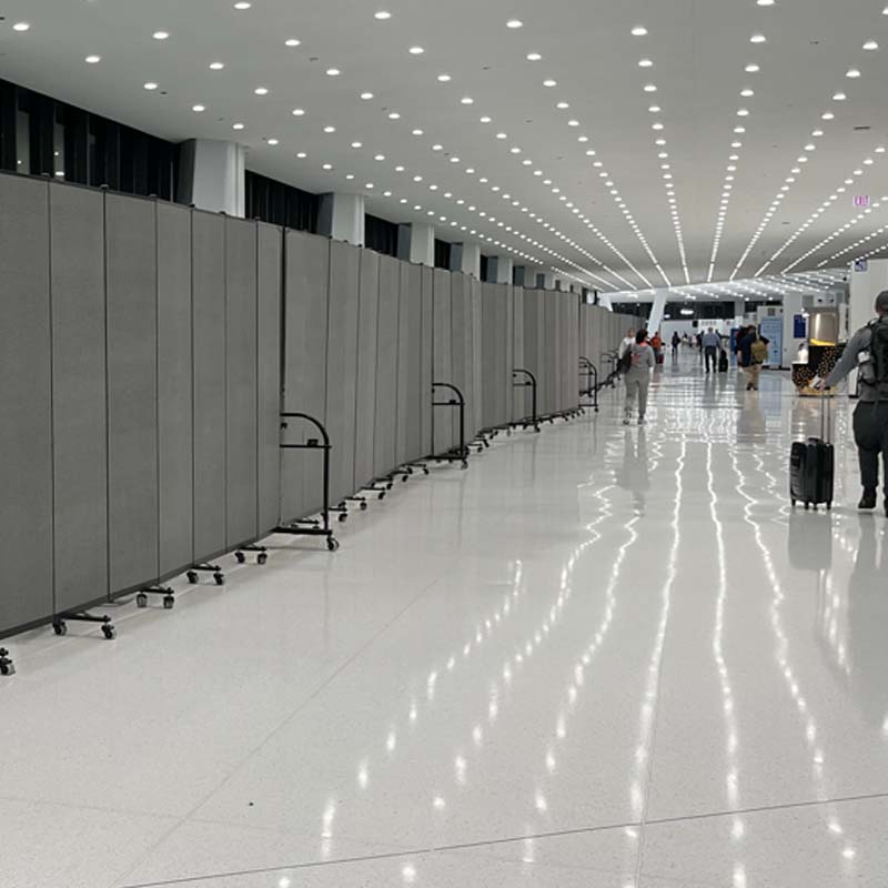 Gray freestanding wall stretches down long airport hallway