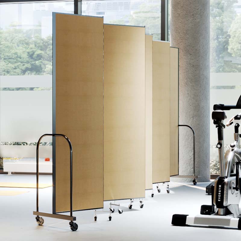 Tan room divider separating fitness equipment from a larger yoga class space