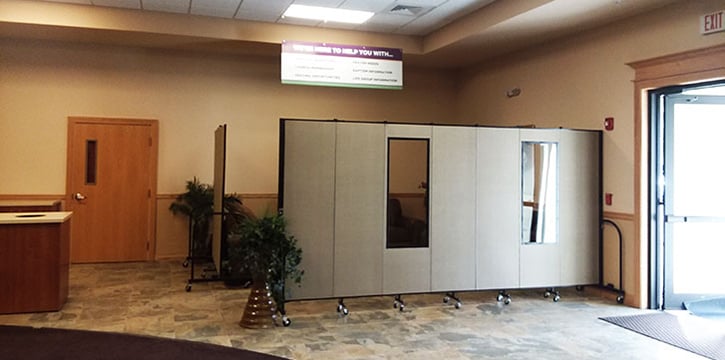 Tan room dividers partially surrounding a seating area by an outdoor entrance