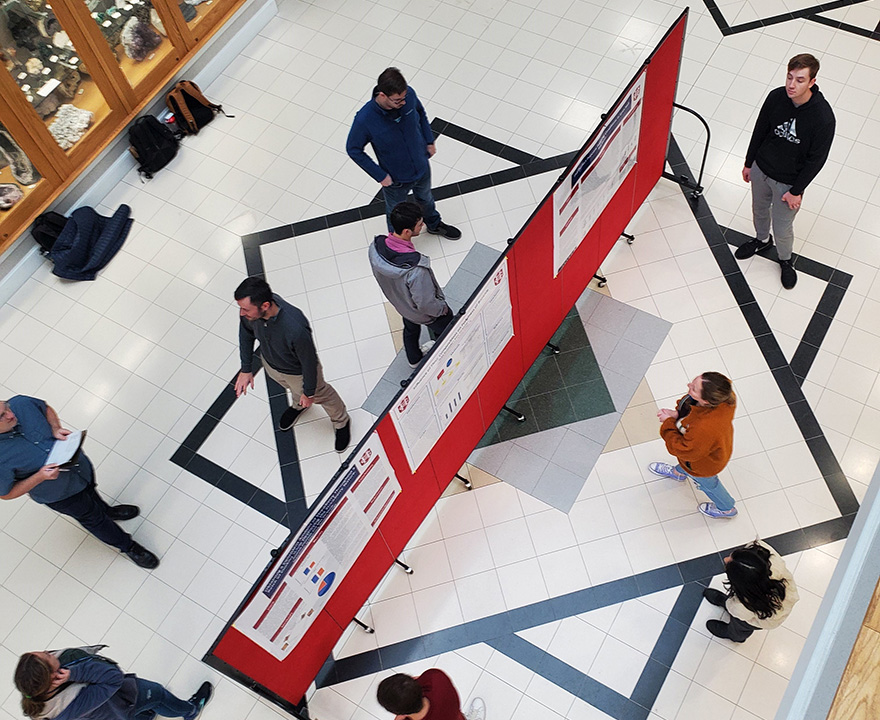 Students standing around a freestanding red bulletin board