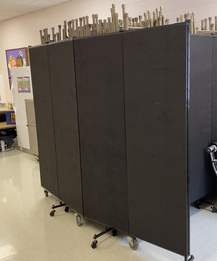 Black room divider hiding chair stacks in hallway