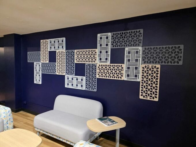 Decorative geometric wall panels mounted above lounge seating in a modern interior.